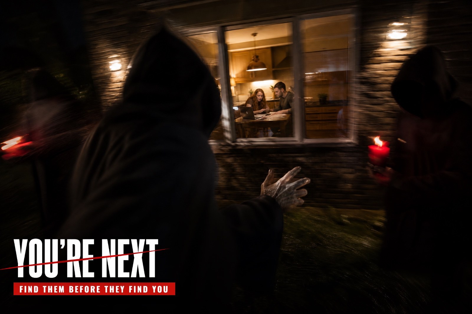 Seen from behind, a couple stands before an abandoned church whose stained glass glows blood red, masked cult members watching from inside